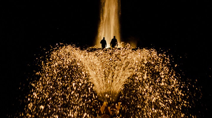 illuminierte Fontaine mit zwei Männern im Licht