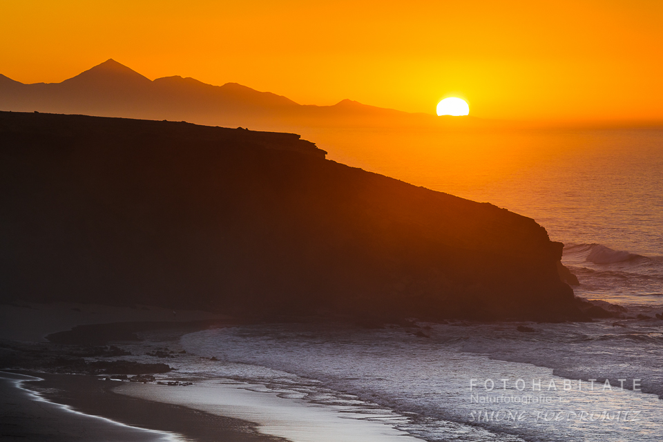 glutoranger Sonnenuntergang hinter Bergen am Meer