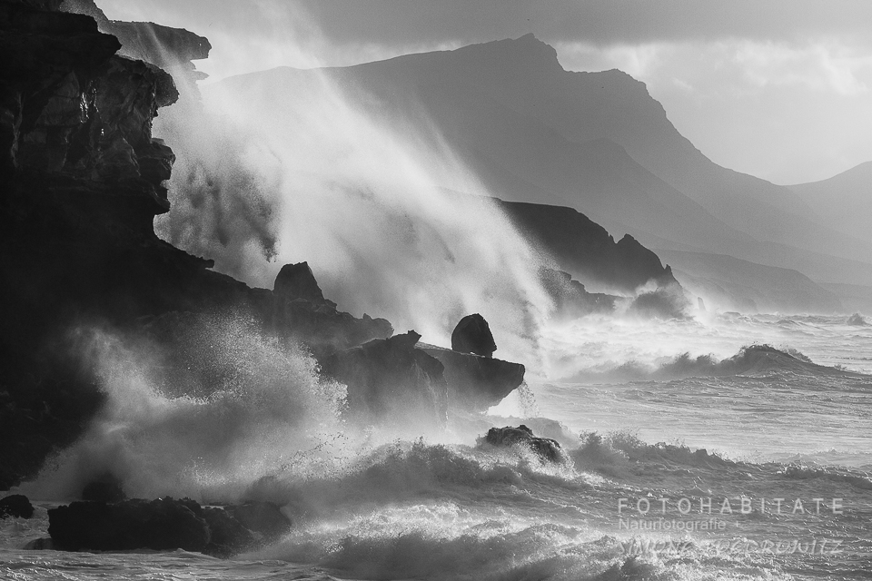 hohe Wellen an Felsklippen in schwarzweiß