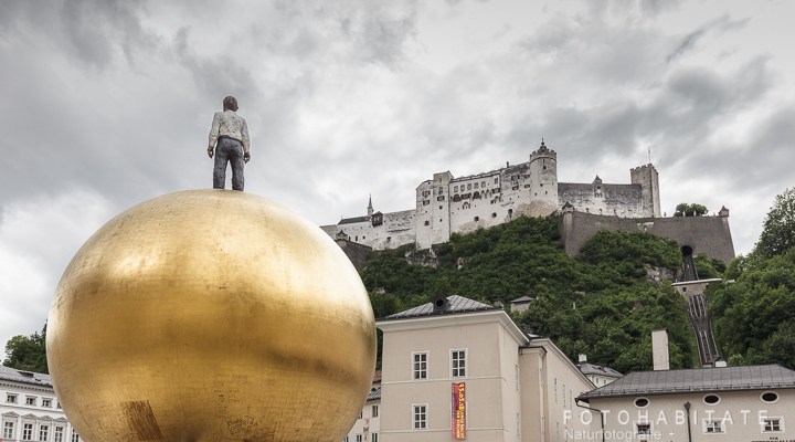 Skulptur Mann auf goldener großen Kugel vor der Festung Salzburgs