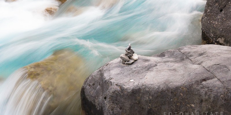fließendes Wasser am Wegweiser aus gestapelten Steinen