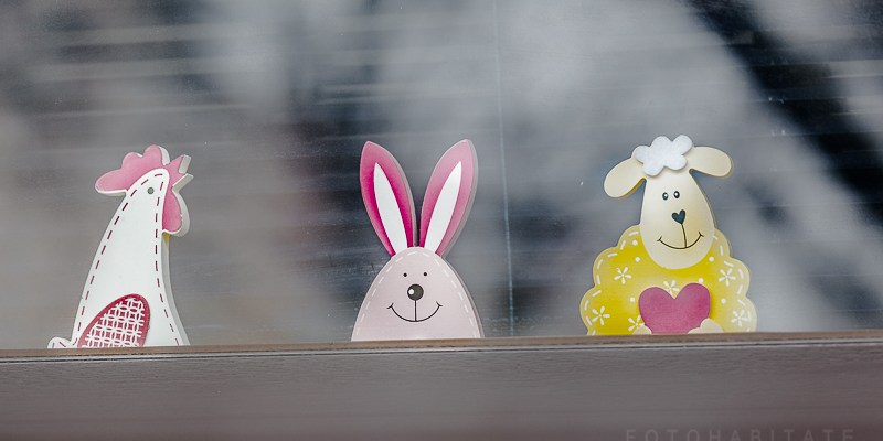 drei Figuren (Huhn, Hase, Schaf) aus Holz hinter Fensterglas