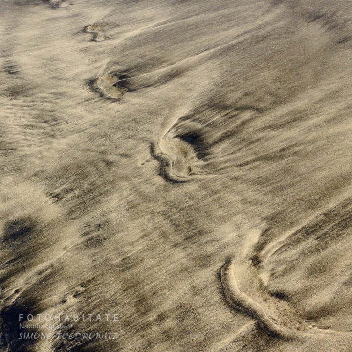 Fußspuren im marmorierten Sand