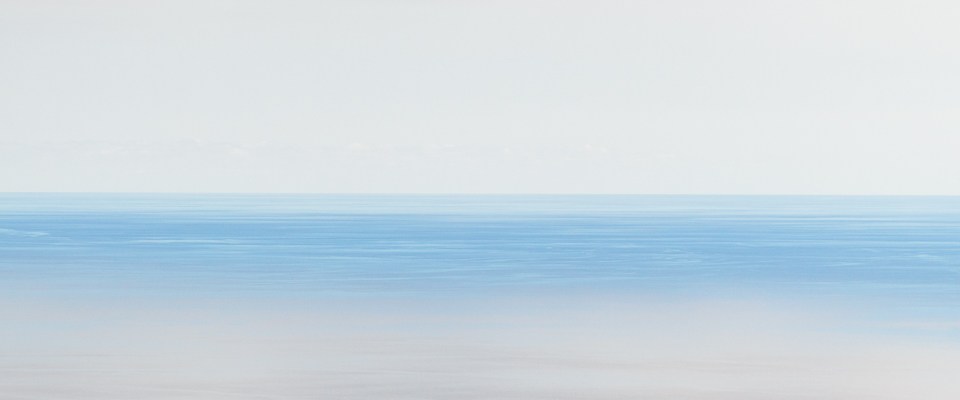 Blauer Meeresstreifen zwischen grauen Wolken und grauem Wasser