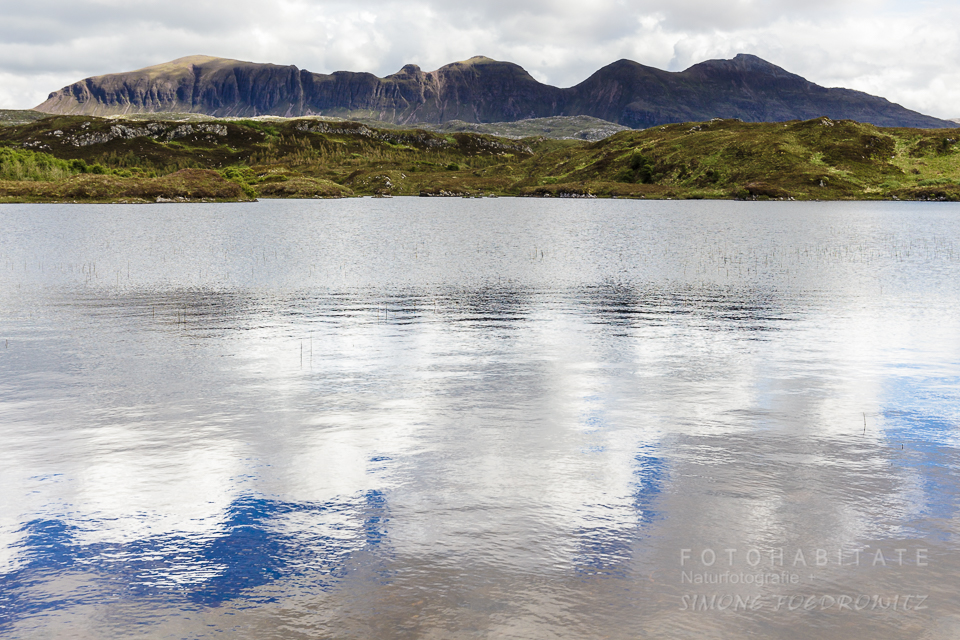 Berge an See, in dem sich Wolken spiegeln