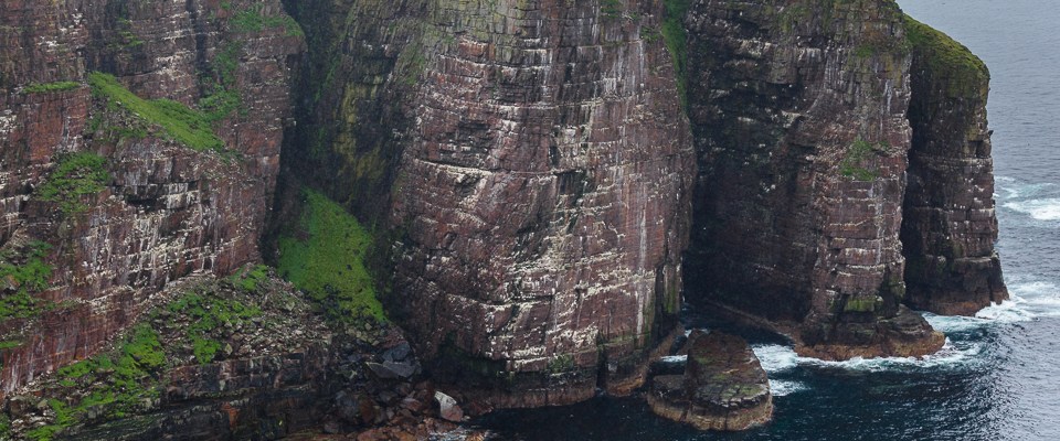 steile tonnenförmige rotfarbene Felsklippen am Meer