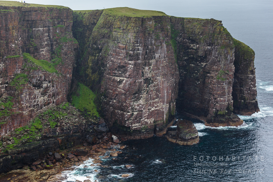steile tonnenförmige rotfarbene Felsklippen am Meer