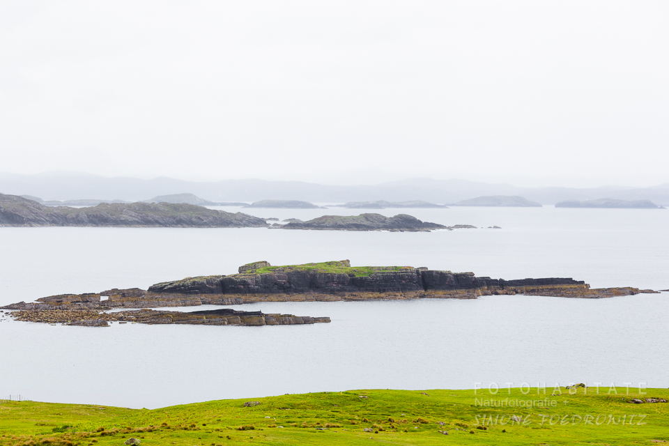 kleine flache Felsinsel in ruhiger See an Küste