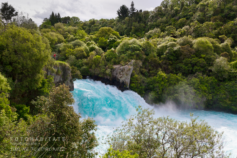 blauer Wasserfall zwische baumbewachsenden Felsen
