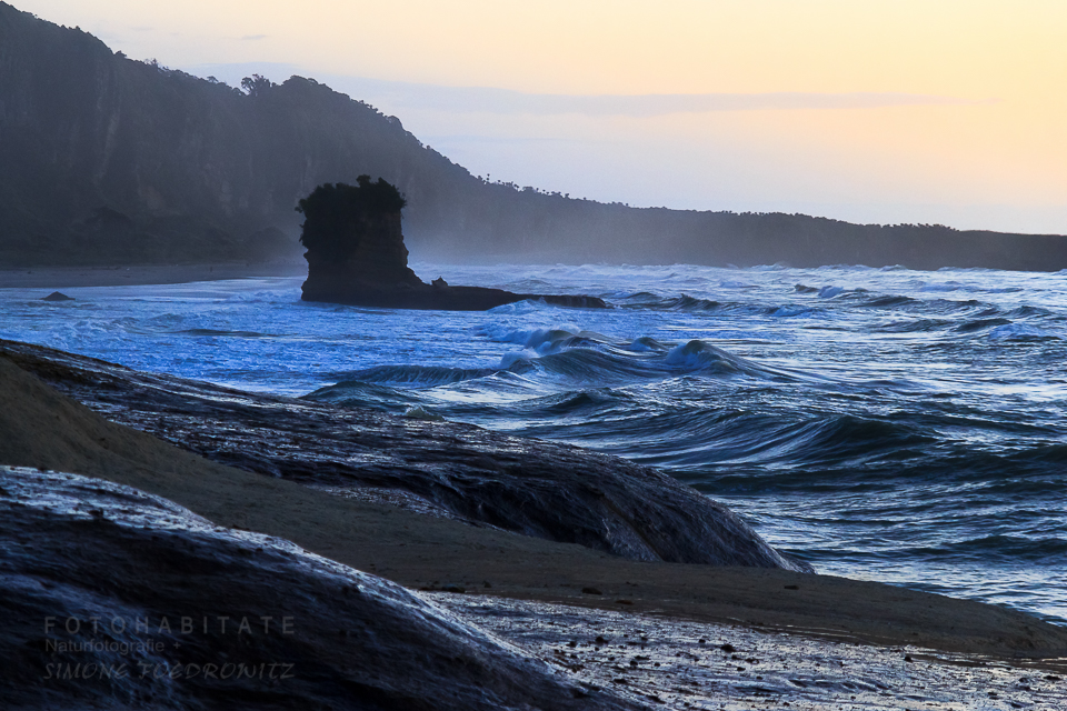 Fels im Meer an Küste zur Blauen Stunde