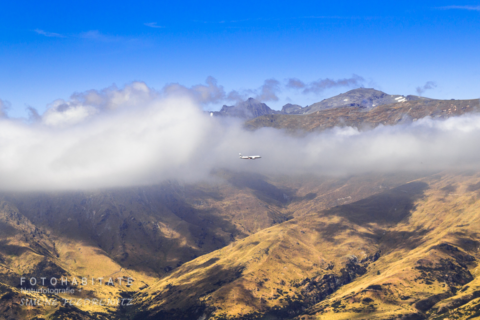 Flugzeug in Wolken vor Bergen im Landeflug