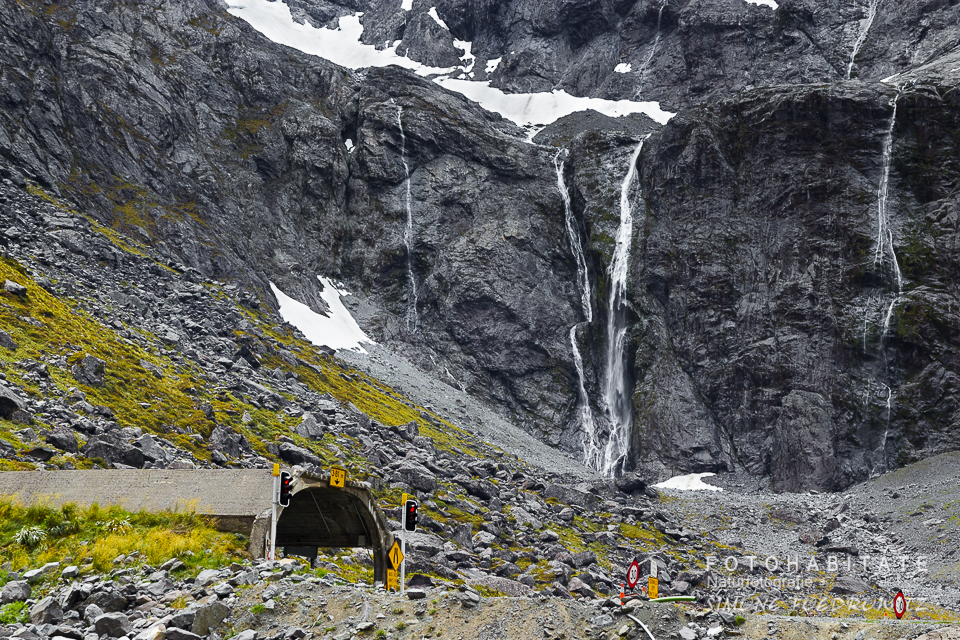 Wasserfälle fließen an Felsen an einem Tunneleingang hinunter
