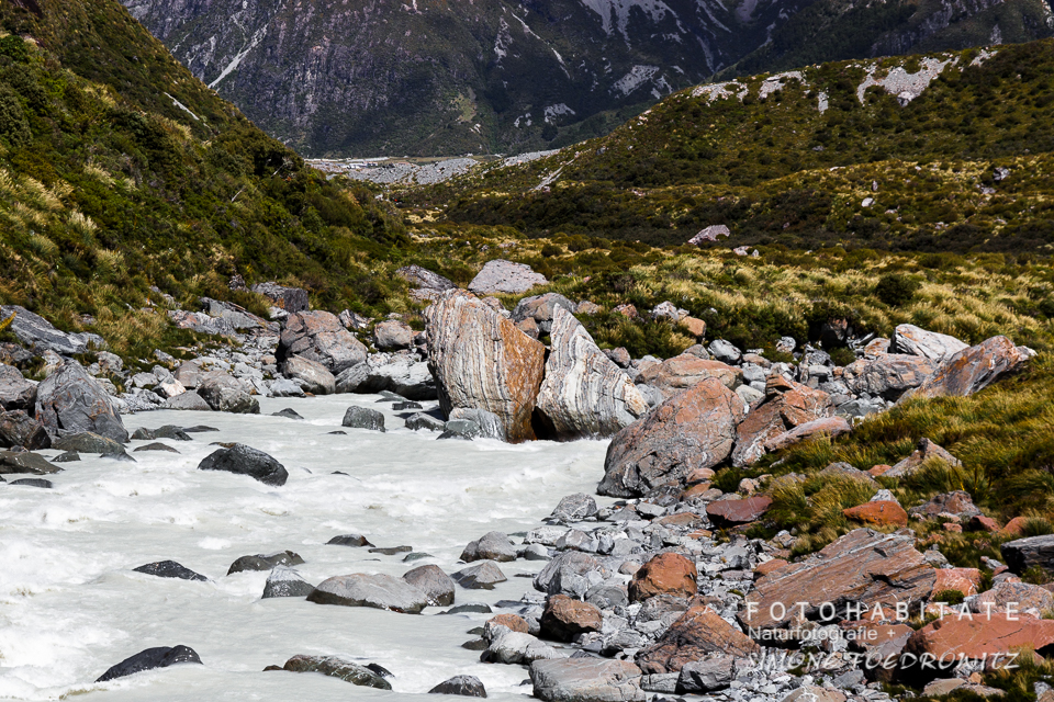 Fluss mit Steinen am Berghang